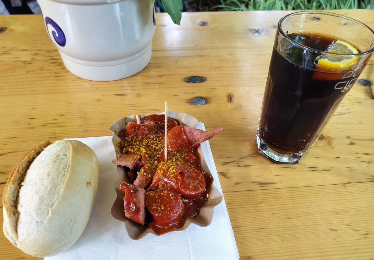 Table with a casual meal: curry sausage, roll, and Coke. The small soda (no refills) is typical for German restaurants.