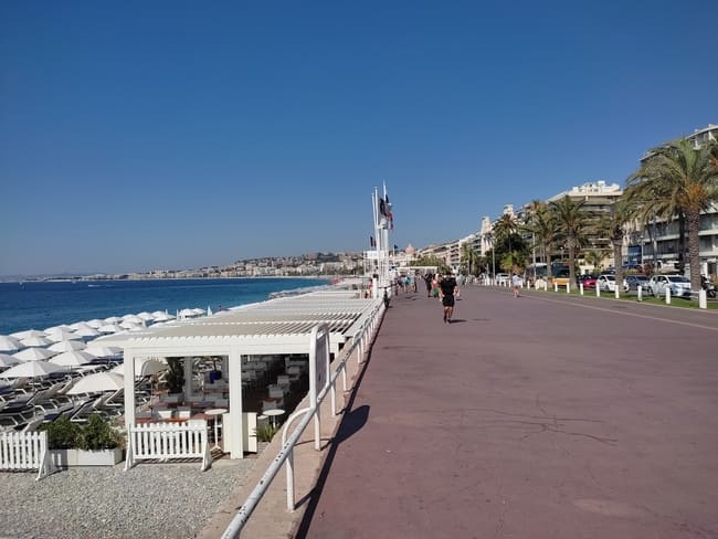 Wide boulevard of Promenade des Anglais with pebble beach on the left