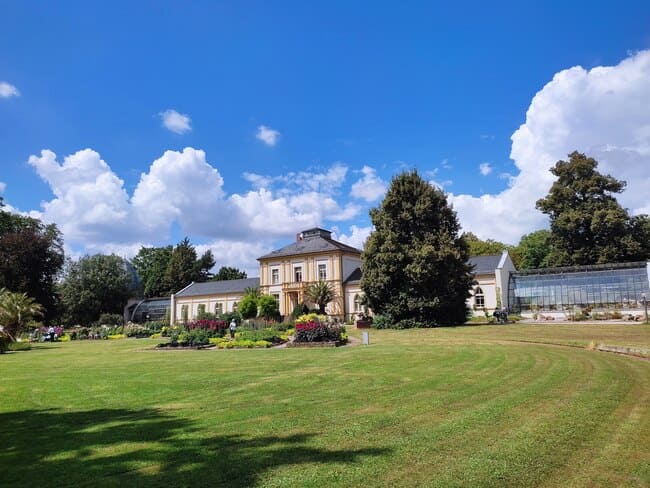 Villa Leonhardi with green house and manicured lawn in front of it