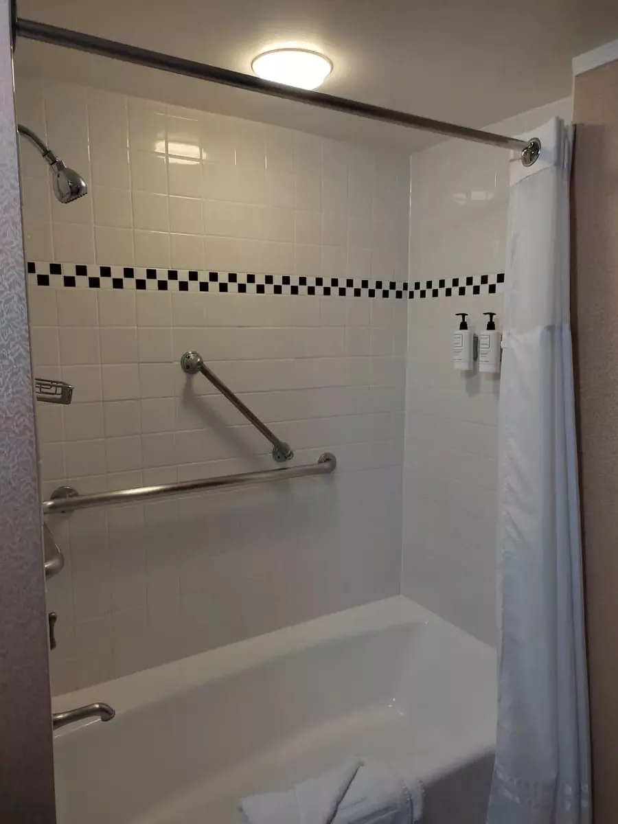 White bathtub with shower curtain and black and white wall tiles in bathroom of cabin A 206 of Queen Mary