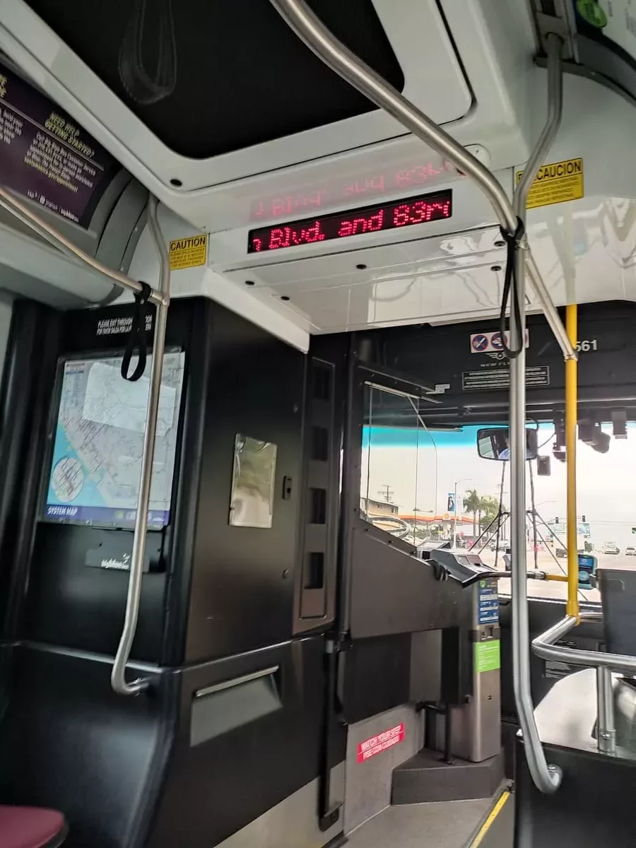 Inside a Big Blue Bus on the way from Santa Monica to LAX. Up front is the fare box and the scanner for tap cards. A sign on top shows the upcoming stop