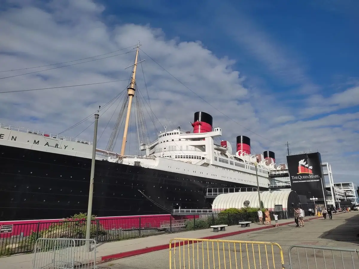 A picture of Queen Mary anchored in Long Beach. There are bridges , tunnels, and elevators connecting the ship to the street.