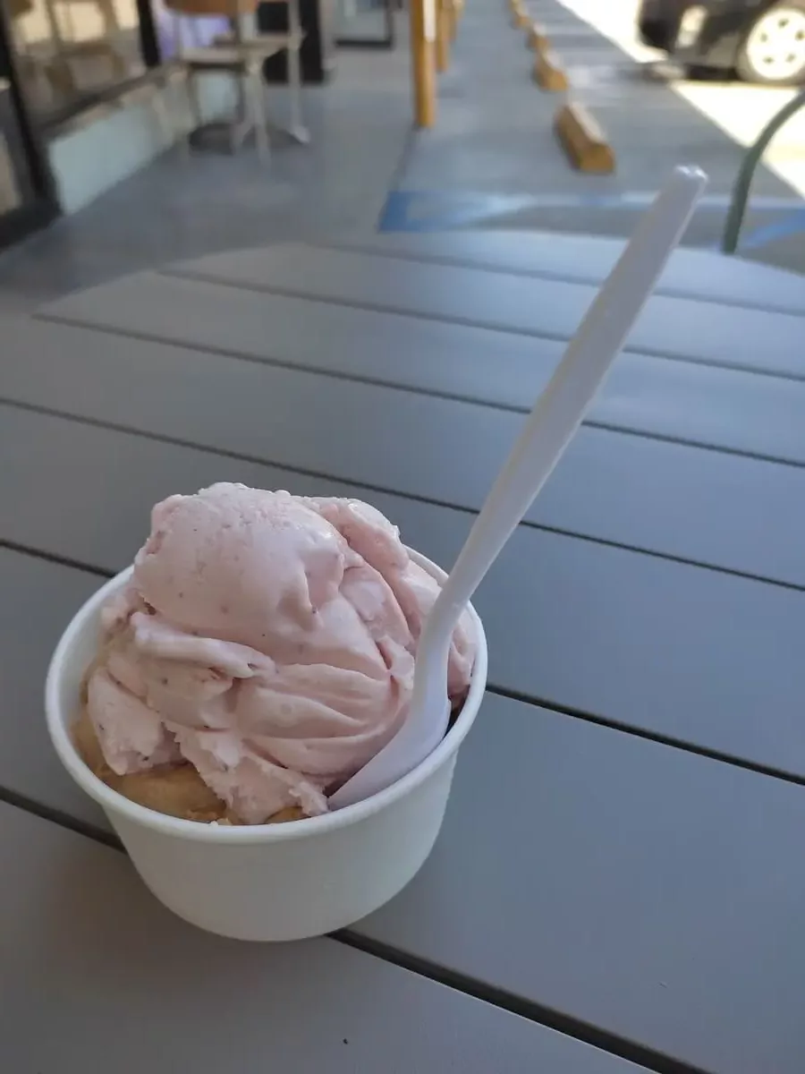 Small tub with spoon and two ice-cream flavors on a small table next to parking spaces