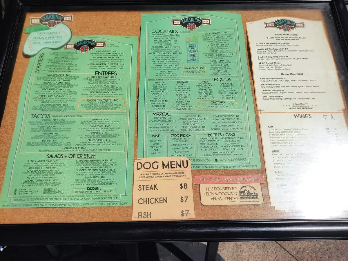 Board with menu of Tamarindo Restaurant in Del Mar. In addition to the usual food and beverage offerings it includes a dog menu with a choice of steak, chicken, or fish