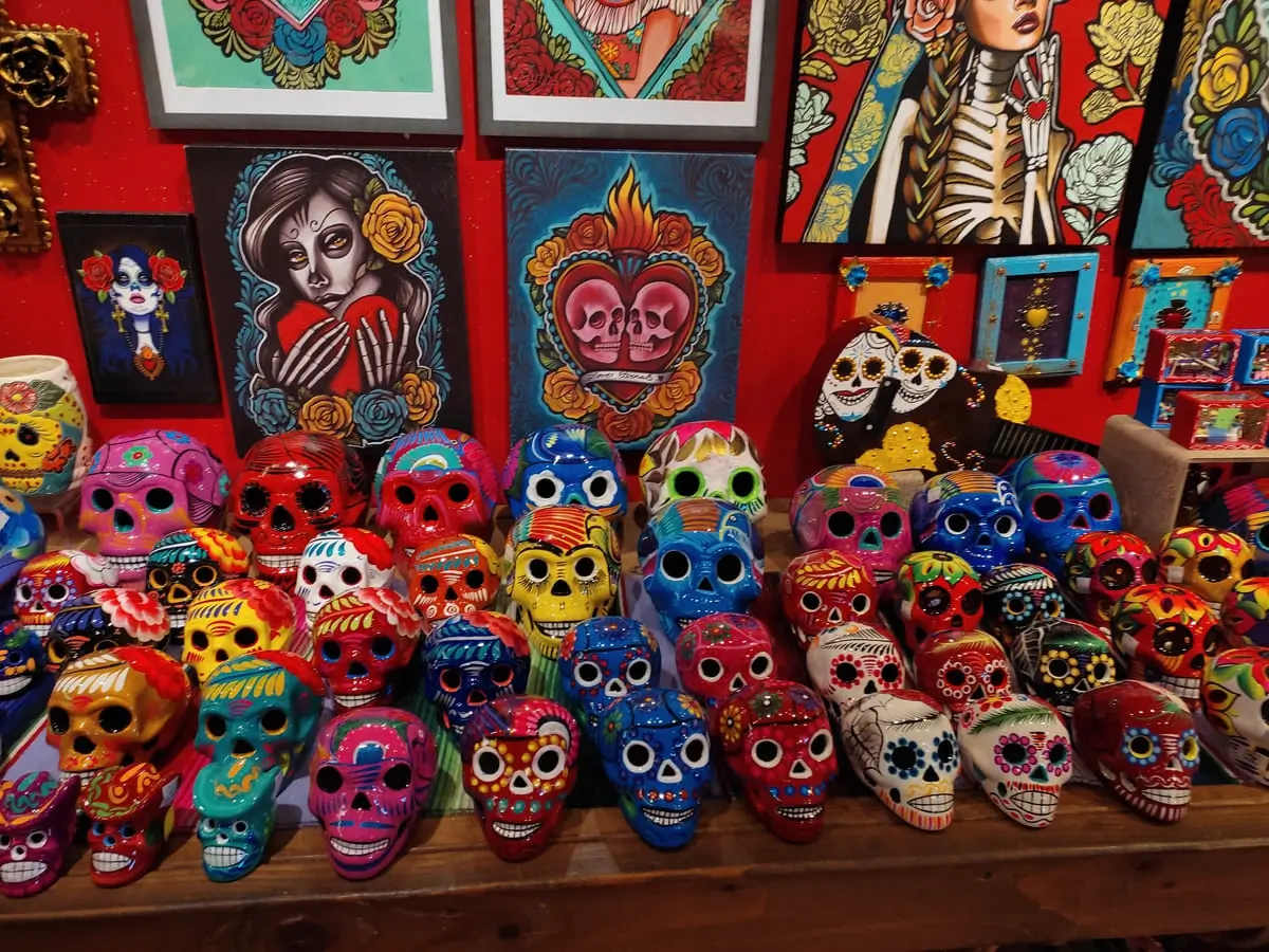 Store display of brightly colored skull decorations and Dia del Muerte inspired paintings