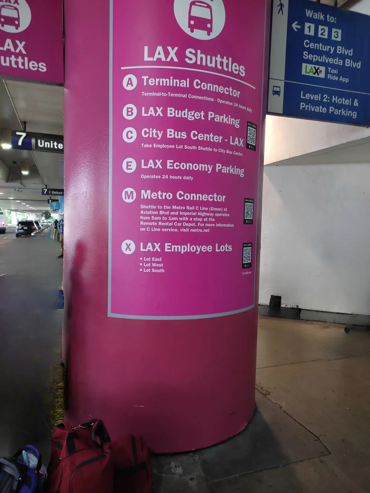 Large pink column in front of terminal 7 at LAX to mark the shuttle stop. Large white writing shows where the different shuttles go.