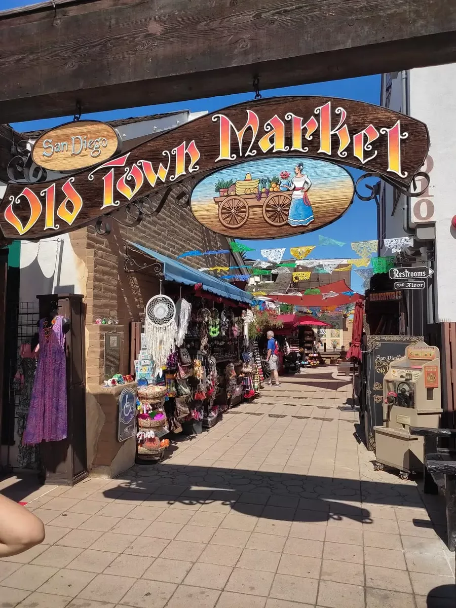 Colorful banner sign for Old Town Market with various stalls selling Mexican-style souvenirs behind it