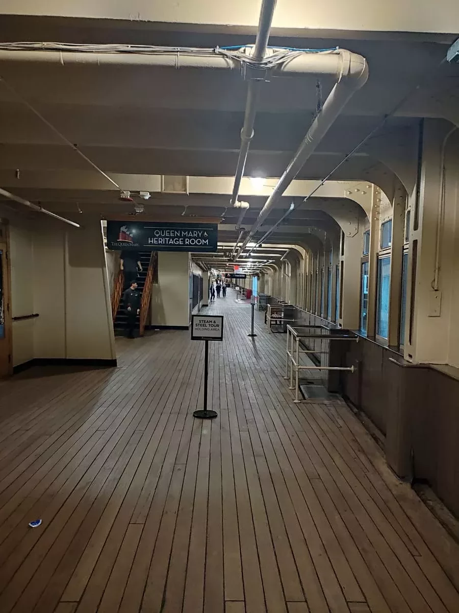 Long promenade deck in the evening with signs for lining up for tours