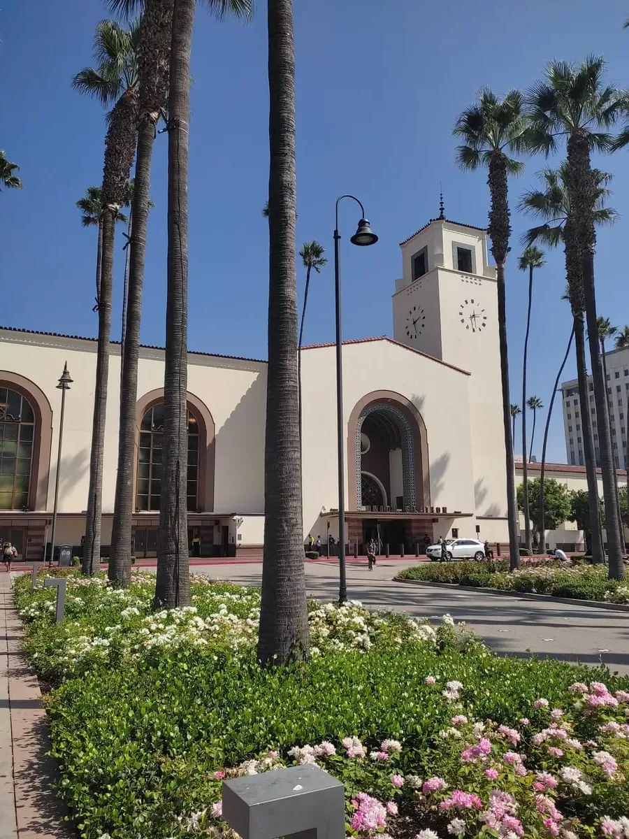 Union Station in downtown LA resembles a large Mexican church. Pink flowers and large palm tree in front of the train station give it an inviting air.