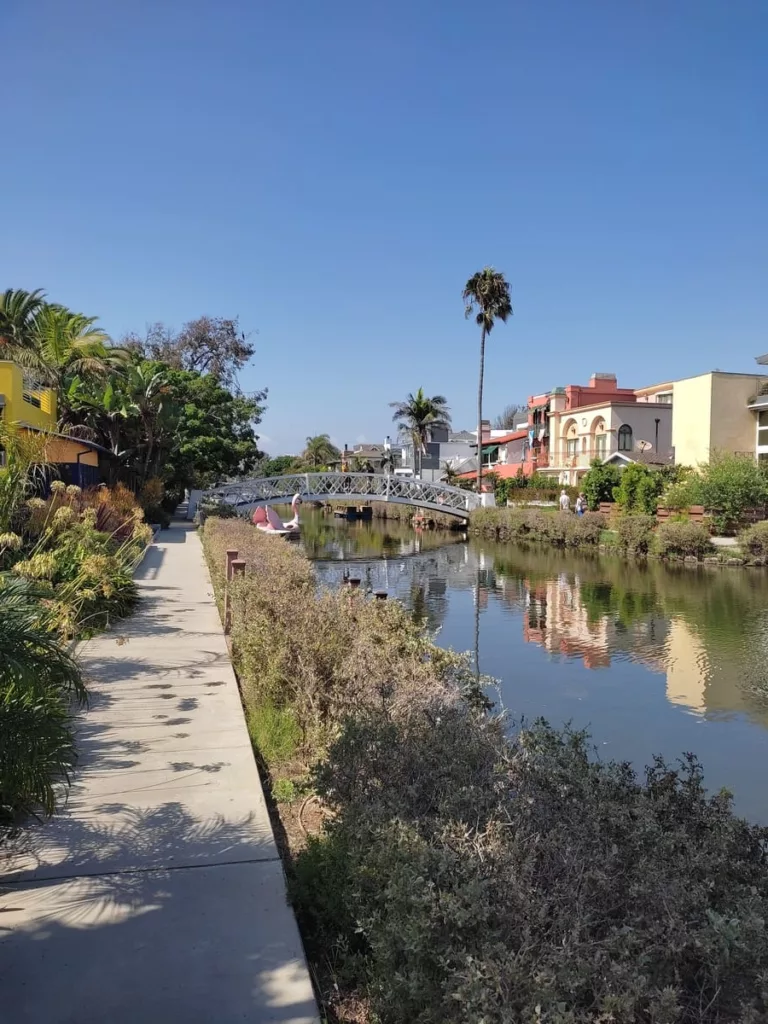 Canal in Venice, California, with walkway, white bridge, pink swan boat and cute cottages along the shore