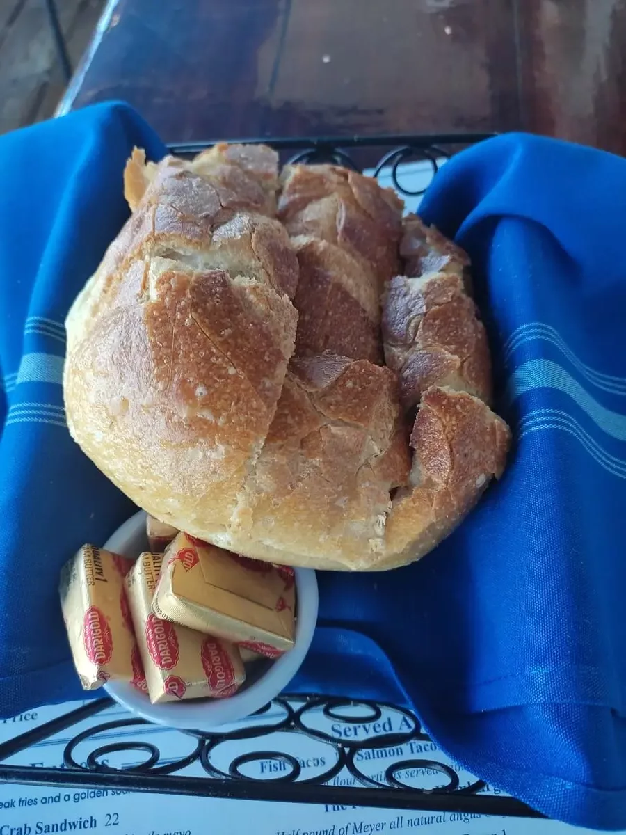 A loaf of freshly baked sourdough bread and a small dish with butter on a blue cloth