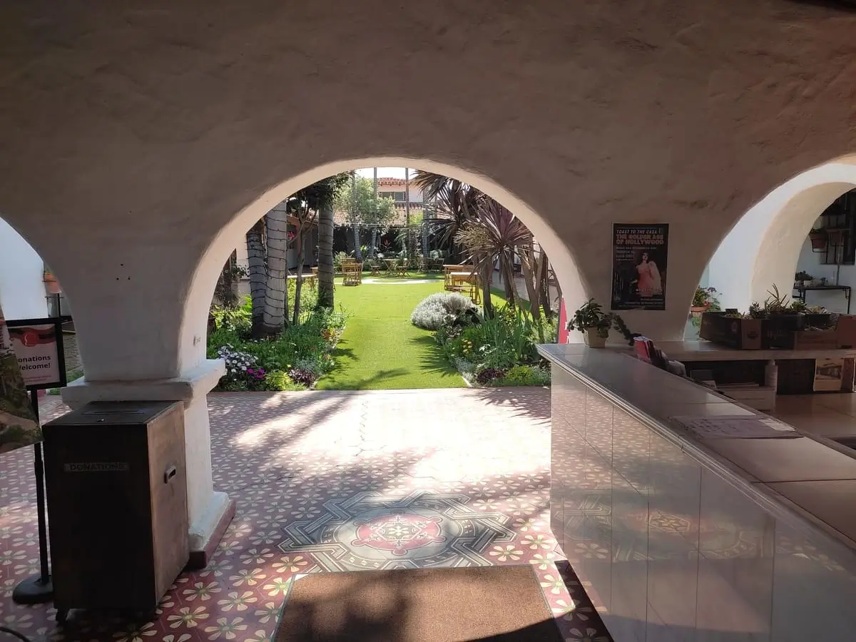 Peeking in through Casa Romantica's entrance gate you see a patterned tile floor and beyond that a pretty courtyard with grass, flowers, and palm trees