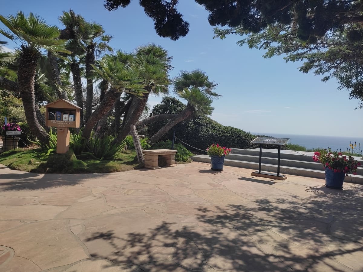 Central Plaza of the Self-Realization Fellowship Gardens in Encinitas with benches and view out to sea. A small cabinet offers various pamphlets of the group