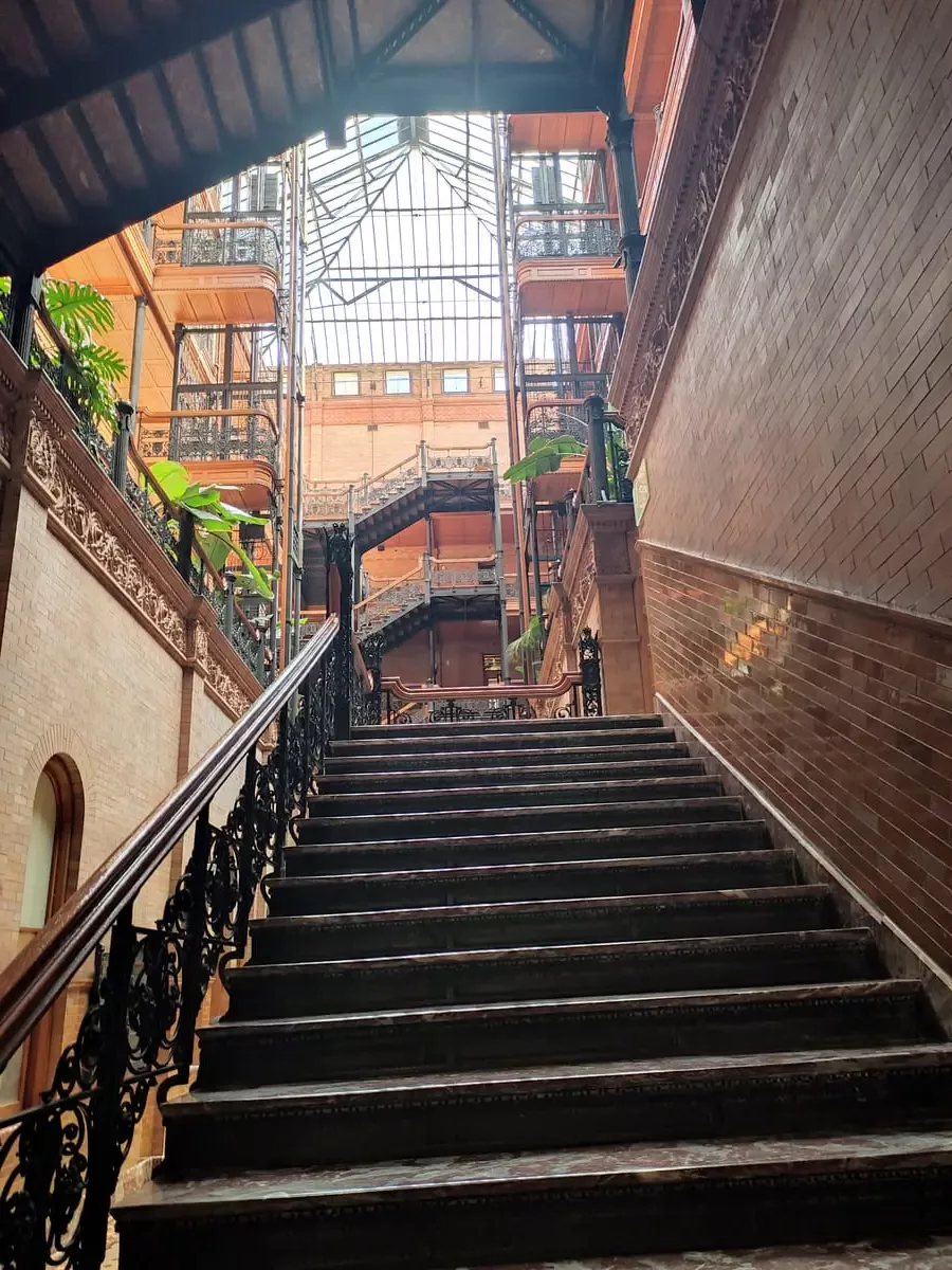 Worn steps with ornate hand rail leading to upper floor in brick Bradbury building