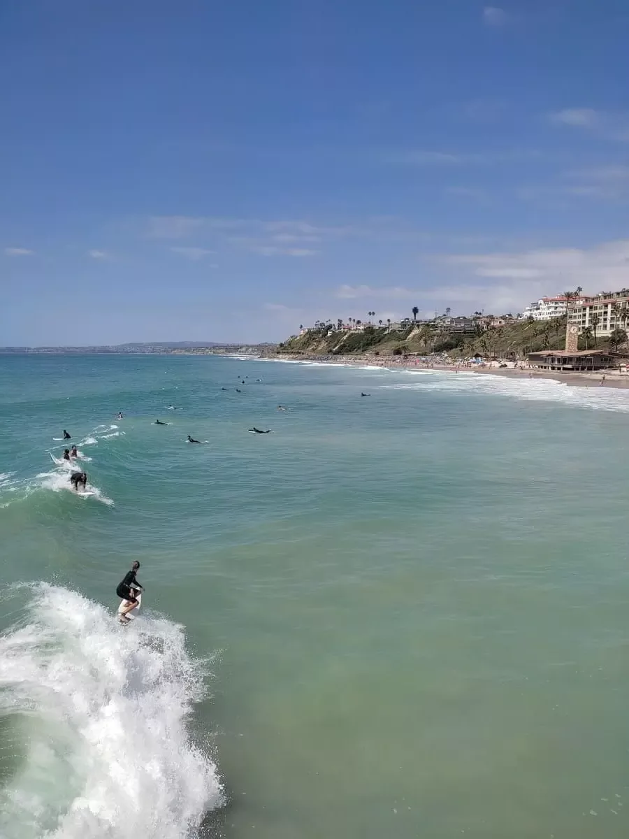 Young surfers riding the waves near the San Clemente Pier