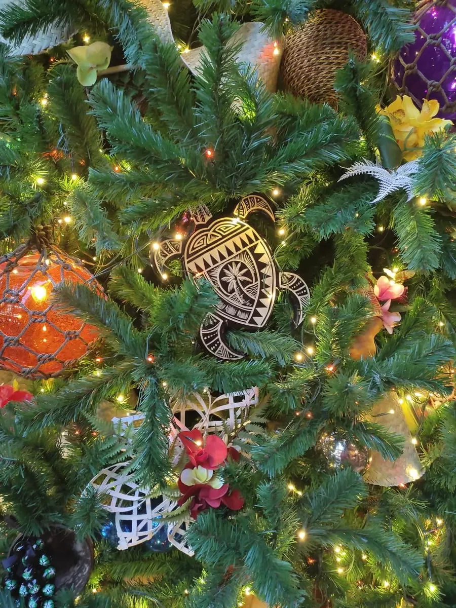 Close-up of Christmas tree decorations with colors mainly orange, white, and dark brown. There are colorful orbs and a turtle shape with a palm tree printed on it.