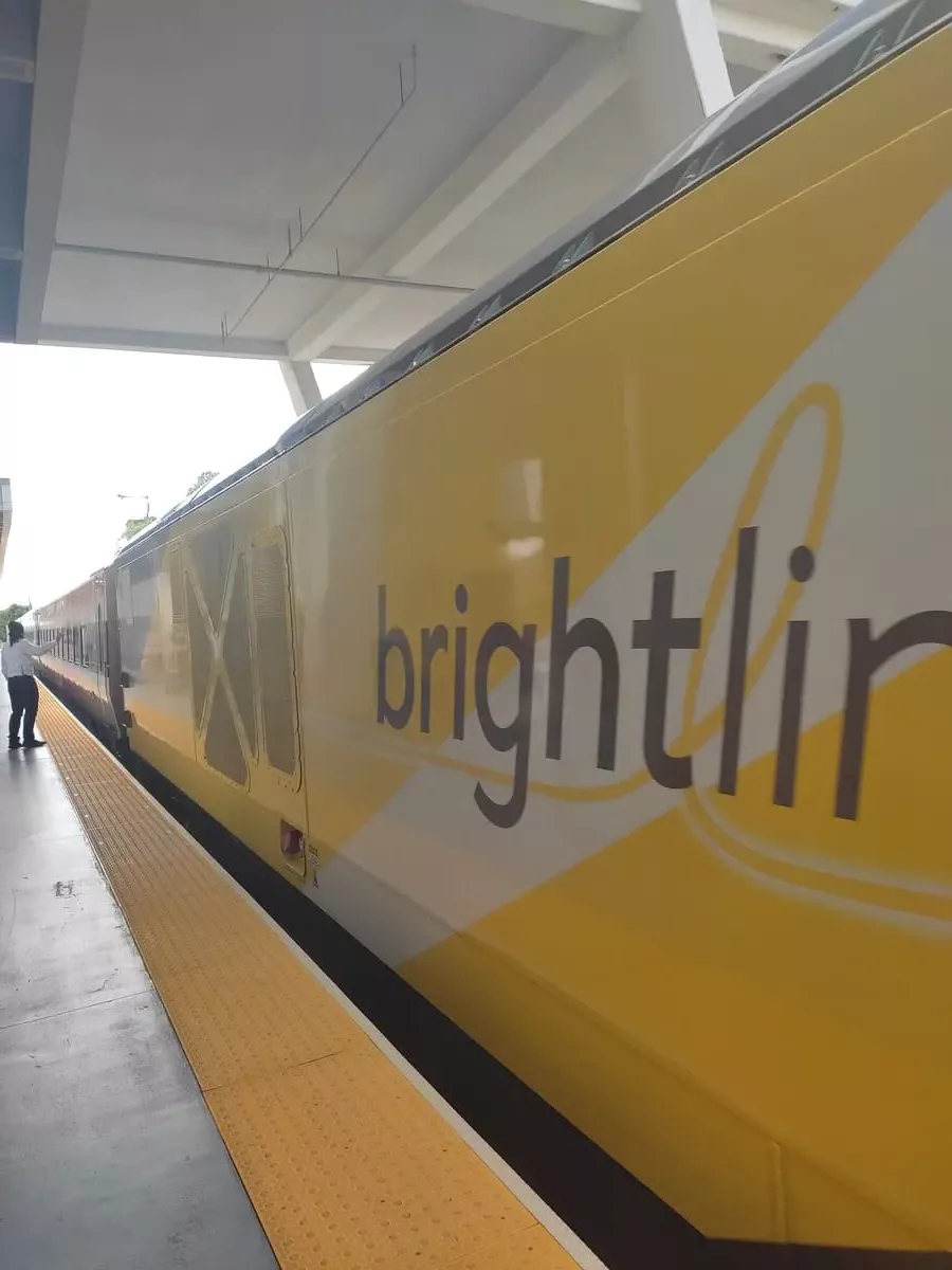 Train with distinctive yellow coloring and writing "Brightline" at platform