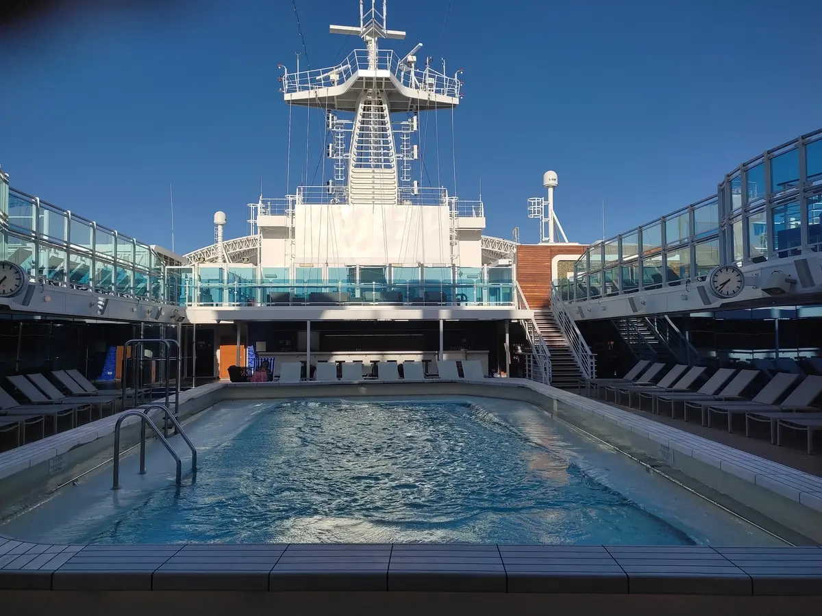 Empty Pool surrounded by sun loungers in Retreat Area on Sky Princess with steps up to higher level