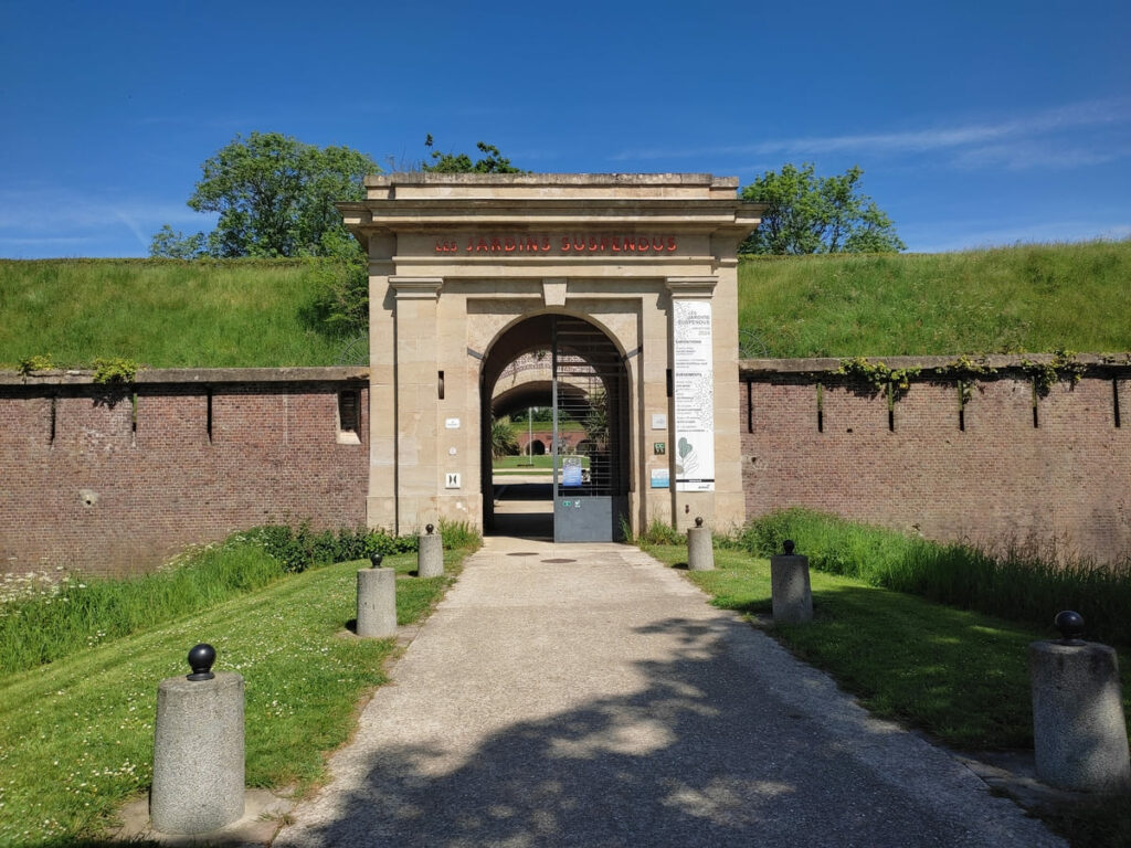 Wall of earth and stone with gate, entrance to Les Jardins Suspendus