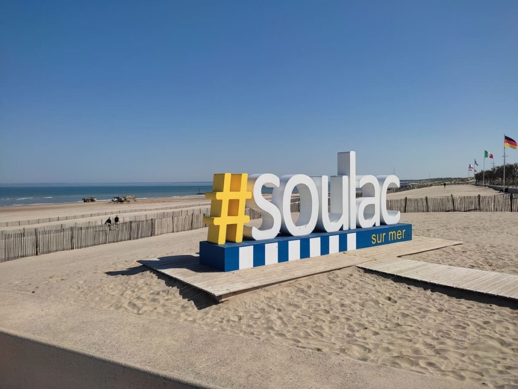 Wide sand beach with large sign soulac sur mer