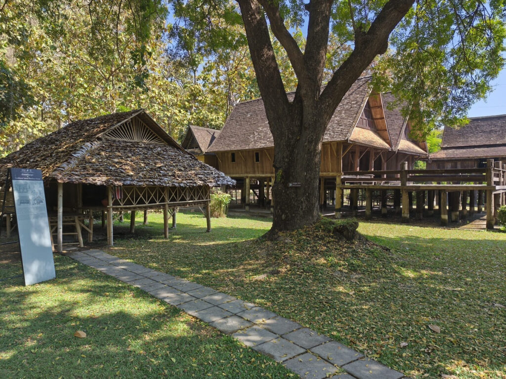 Traditional wooden houses clustered around a grassy area with trees