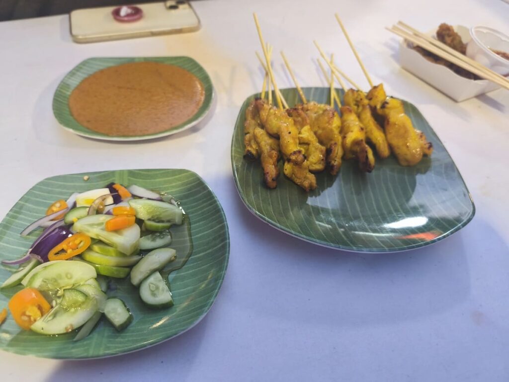 Plates with Chicken and Pork Satay, cut up vegetables, and peanut sauce