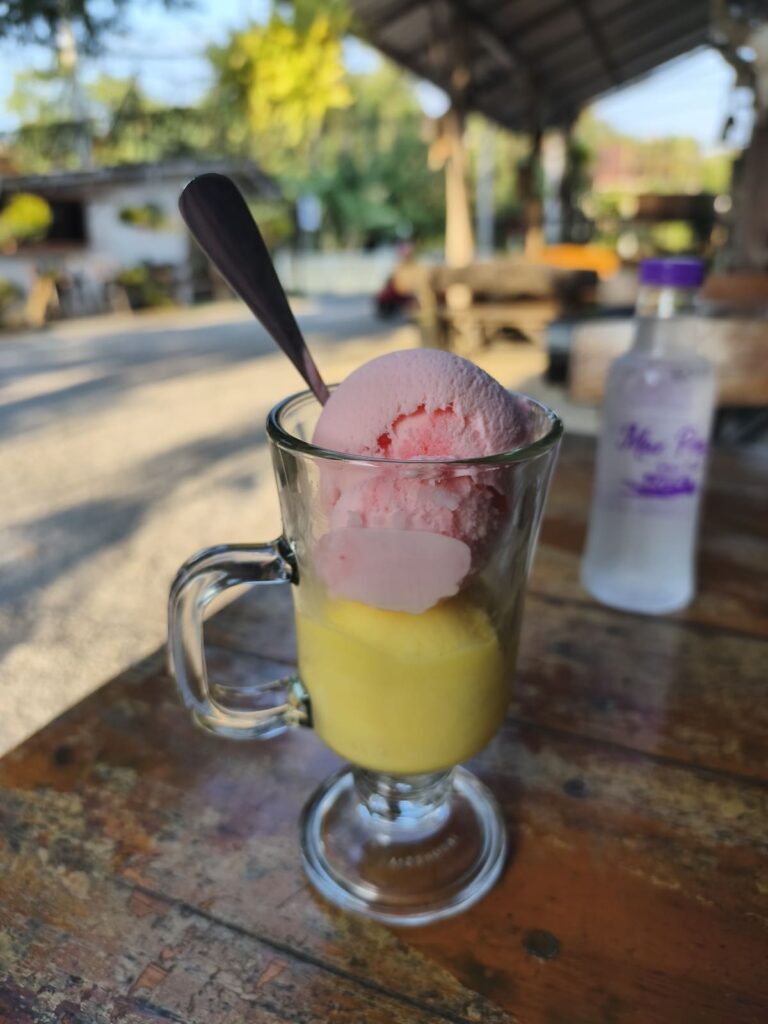 Glass with two scoops of ice cream: yellow (mango) and pink (strawberry)