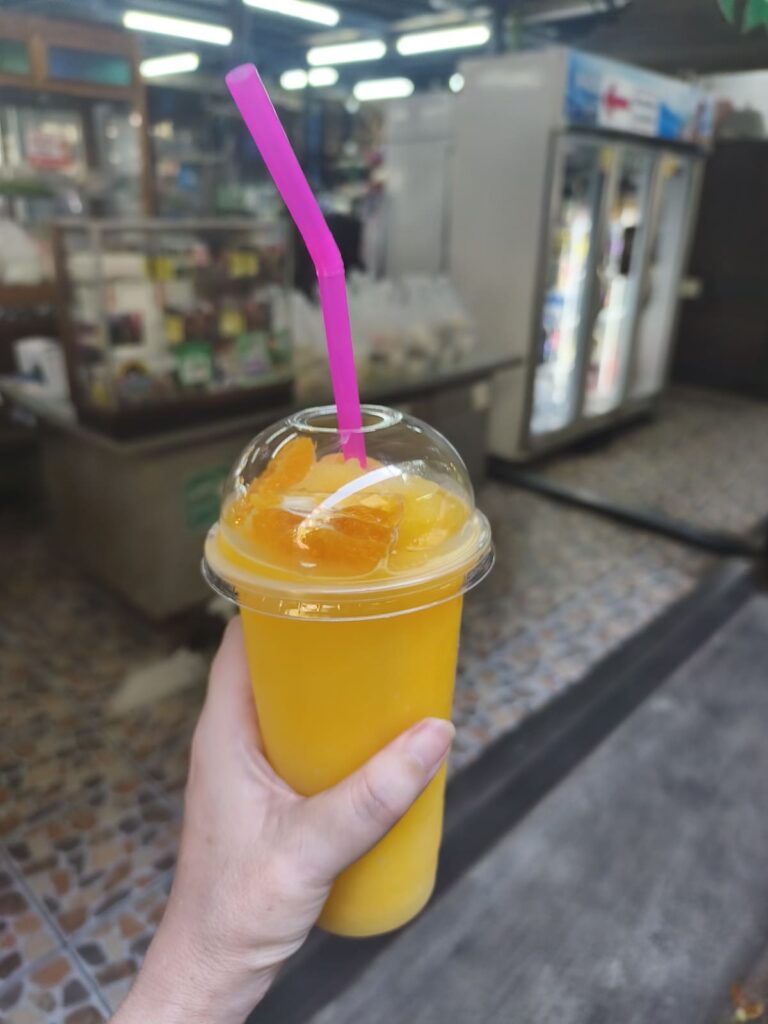 Hand holding cup with orange smoothie