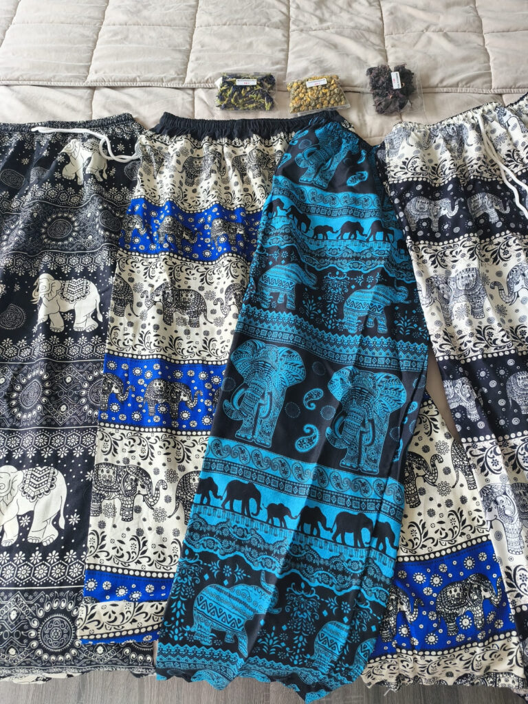 4 pairs of elephant pants and small tea packs on bed