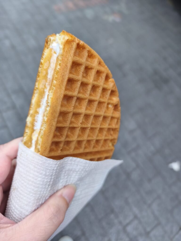 Hand holding a waffle sandwhich with filling