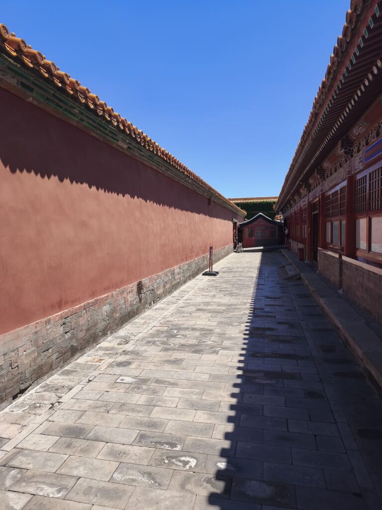 Long corridor lined by high red walls