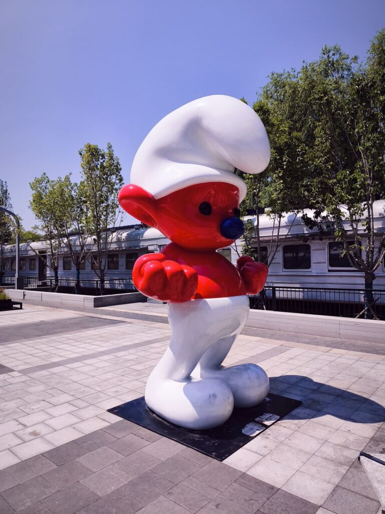 Large red smurf in front of train at 798 Art Zone